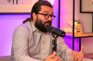 Pastor André Aneas participa de podcast falando ao microfone em estúdio.