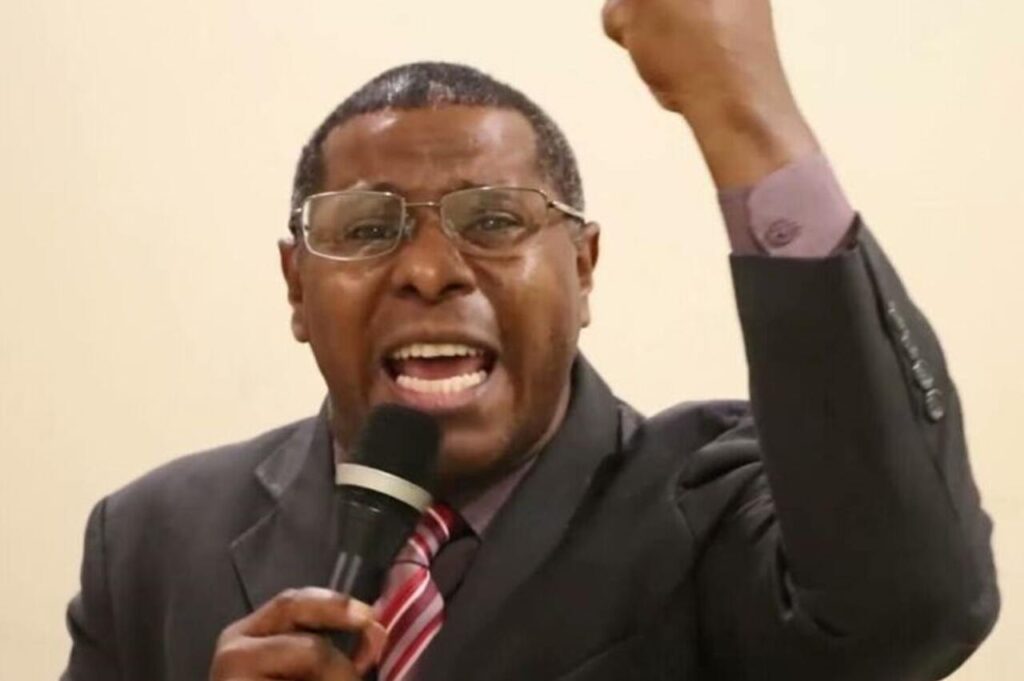 Pastor Osiel Gomes pregando com microfone e braço levantado durante culto evangélico.