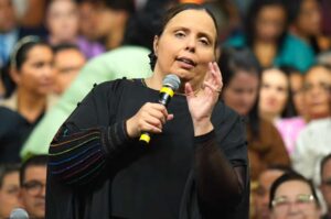 Pastora Helena Raquel ministrando com microfone diante de congregação.