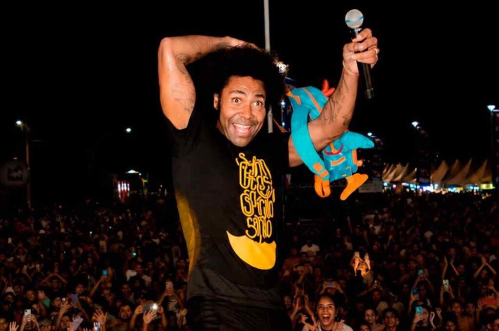 Thalles Roberto canta diante de multidão durante apresentação em evento noturno.