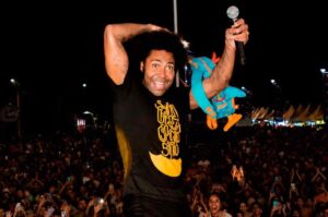 Thalles Roberto canta diante de multidão durante apresentação em evento noturno.