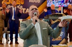 Pastor Marcos Pereira prega segurando um microfone e uma Bíblia durante culto realizado em templo evangélico.
