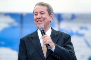 R. R. Soares segura um microfone enquanto sorri durante uma pregação em evento religioso.