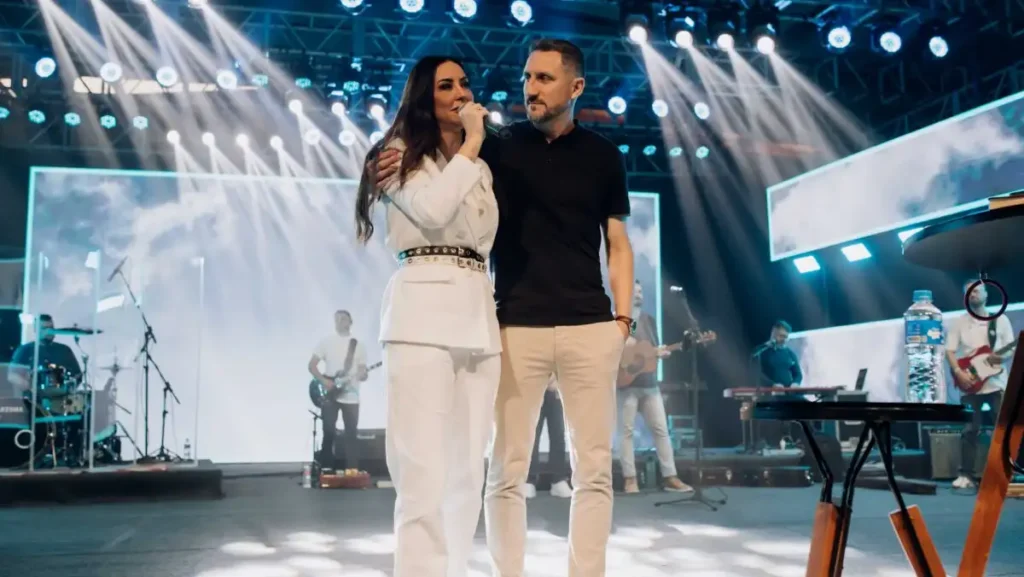 Viviane e Telmo Martinello aparecem juntos no palco durante evento religioso