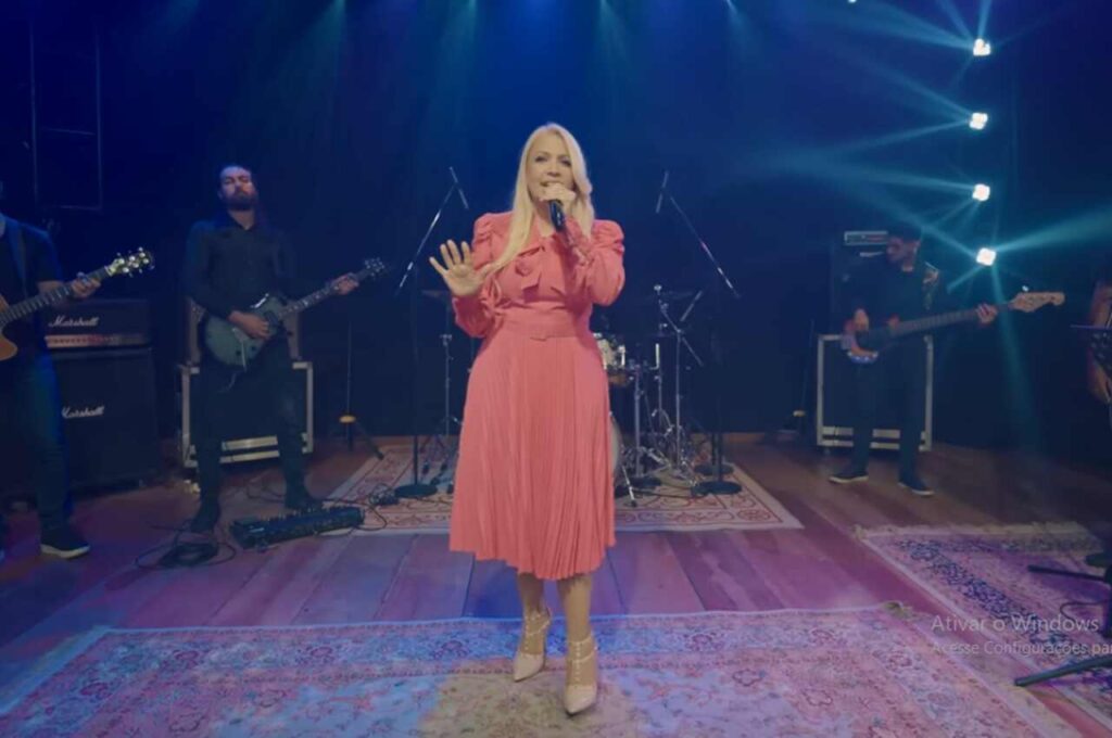A cantora Andrea Fontes se apresenta ao vivo em um palco, cantando com banda durante uma apresentação gospel.