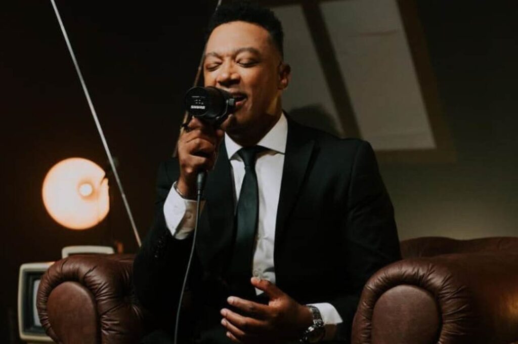 O cantor Marquinhos Gomes interpreta uma canção gospel em estúdio, diante de um microfone durante gravação musical.