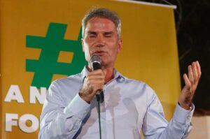 O pastor Márcio Poncio discursa em um evento público, segurando um microfone durante uma manifestação ao ar livre.