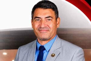 Pastor Marcos Valença posa para retrato oficial usando terno cinza e gravata azul, em imagem institucional de seu ministério.