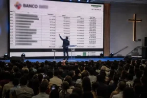 Pastor apresenta extratos bancários e valores financeiros em telão durante culto em igreja lotada