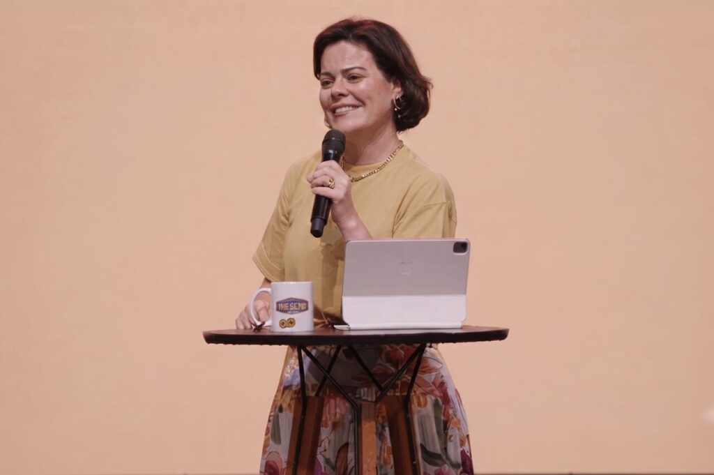 Cantora e pastora Ana Paula Valadão ministra mensagem segurando um microfone durante conferência cristã