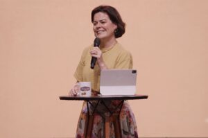 Cantora e pastora Ana Paula Valadão ministra mensagem segurando um microfone durante conferência cristã
