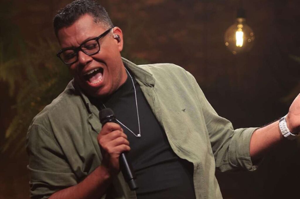 Anderson Freire canta ao vivo segurando um microfone durante apresentação.
