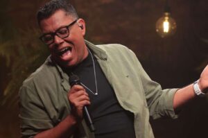 Anderson Freire canta ao vivo segurando um microfone durante apresentação.