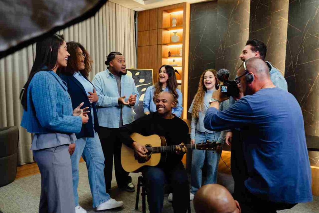 Grupo de músicos do Get Worship participa de gravação em ambiente interno, com cantor ao centro tocando violão.