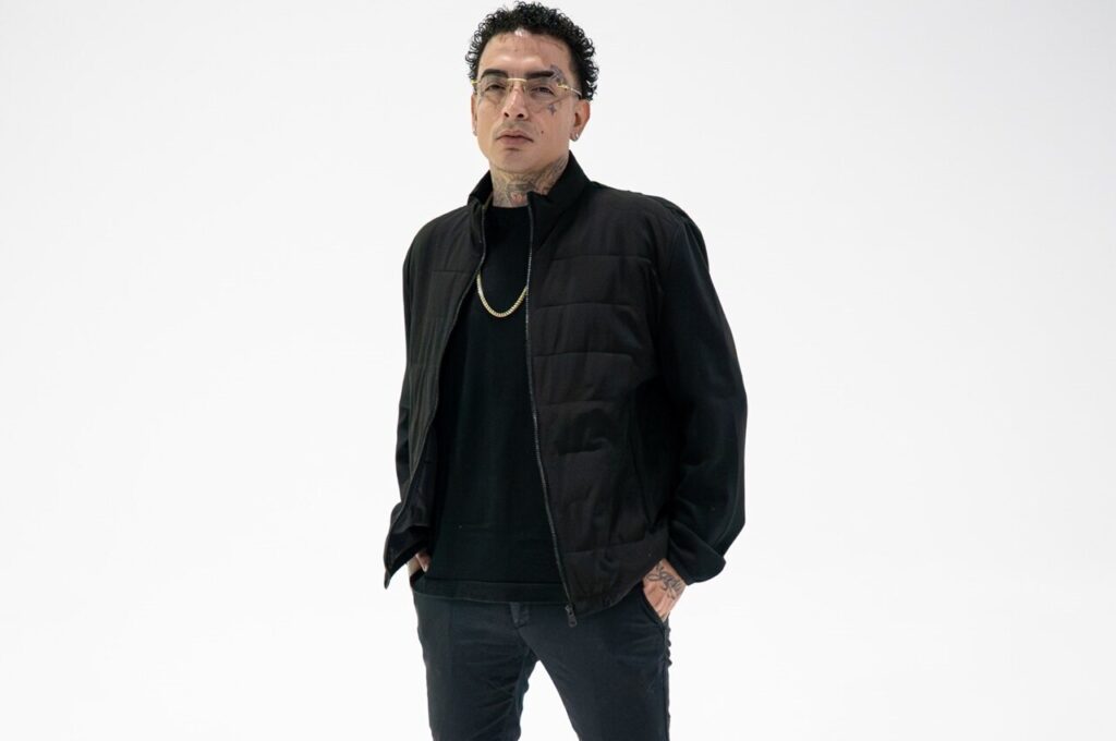 MC Guimê posa para foto usando roupa preta e óculos em fundo branco