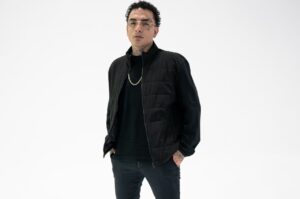 MC Guimê posa para foto usando roupa preta e óculos em fundo branco