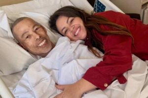 Cantor gospel Marquinhos Meneses sorri em leito hospitalar ao lado da esposa, que o abraça durante visita no hospita