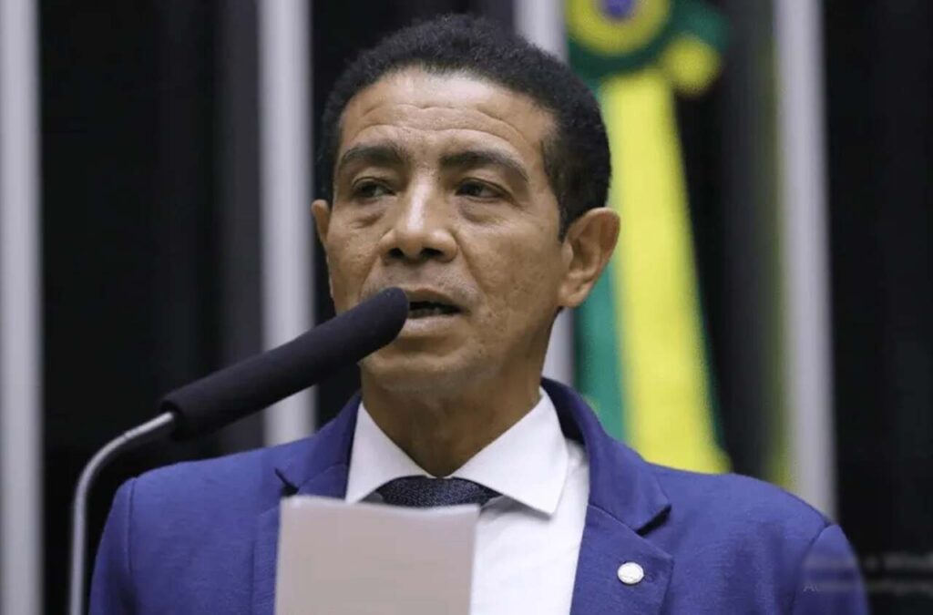 Homem de terno azul fala ao microfone durante um pronunciamento.