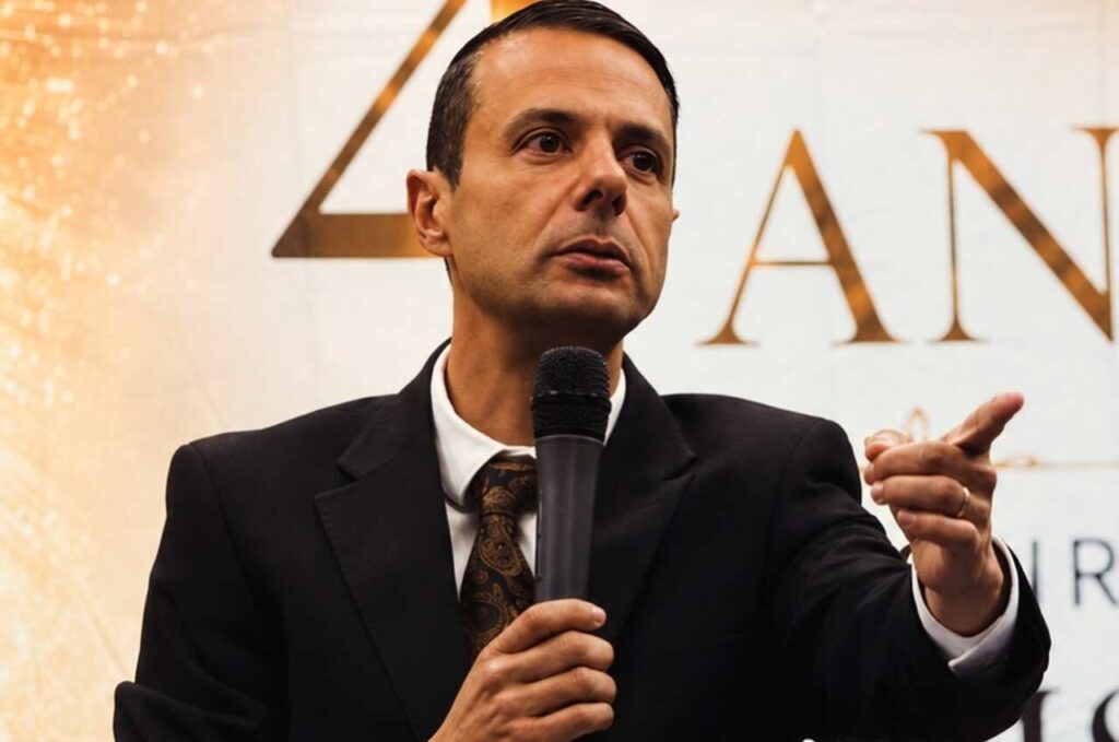 Pastor Juliano Fraga ministra com microfone durante evento religioso.