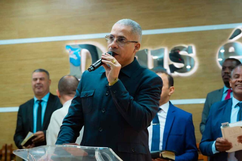Pastor Júnior Trovão prega ao microfone diante de uma congregação.