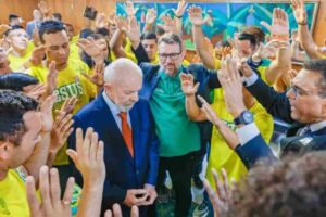 Presidente aparece cercado por pessoas com as mãos levantadas durante momento de oração.