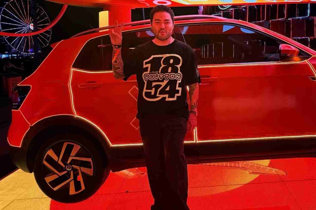 Yude Tamashiro posa ao lado de carro durante evento