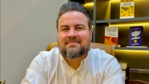 Pastor Pedro Medina sentado em escritório com livros cristãos ao fundo