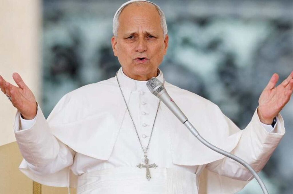 Papa Leão XIV vestido de branco, com os braços abertos diante de um microfone durante pronunciamento público.