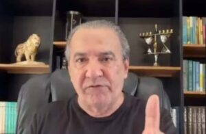 Silas Malafaia aparece em vídeo usando camiseta preta, sentado em uma cadeira diante de uma estante com livros e objetos decorativos, enquanto gesticula com o dedo indicador levantado.